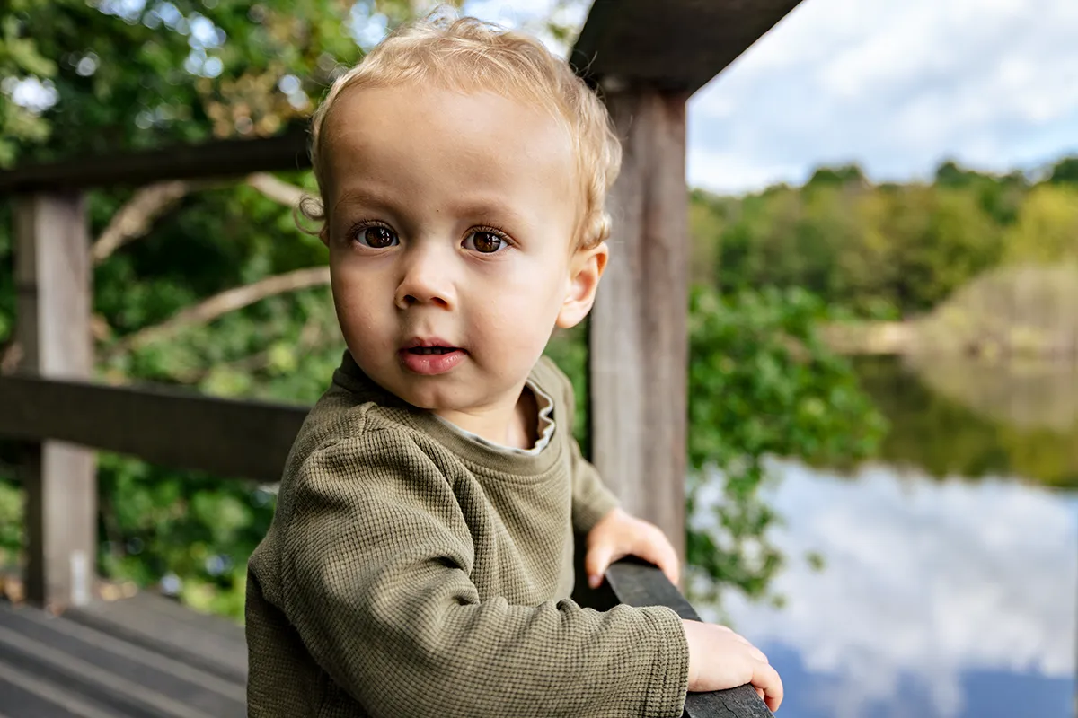 Eliah staat op de steiger en kijkt in de lens. Hij heeft grote bruine ogen die vol nieuwsgierigheid kijken, zin om alles te ontdekken.